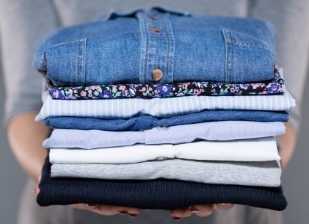 woman holding stack of shirts